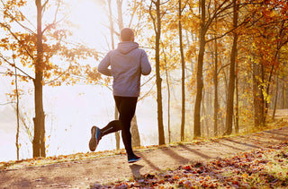 Un homme fait de la course à pied dans une forêt d'automne 