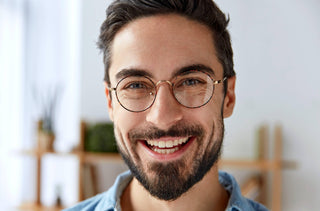 Un homme avec des lunettes sourit à la caméra 