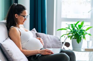 Une femme enceinte navigue sur son ordinateur portable