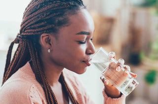 Une femme s'hydrate avec un verre d'eau