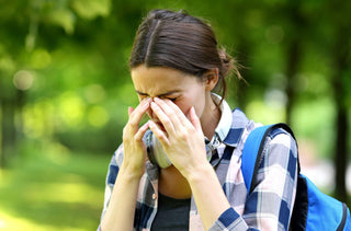 Une femme à l'extérieur avec des yeux qui démangent à cause d'allergies 