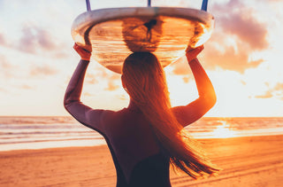 Une surfeuse tient sa planche sur sa tête