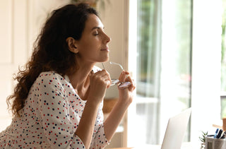 Une femme fait une pause sur son ordinateur pour reposer ses yeux.