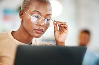 Une femme avec des lunettes lit quelque chose sur son ordinateur