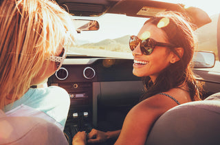 Deux femmes en voiture décapotable avec lunettes solaires 