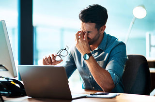 Un homme avec les yeux fatigués travaille à son bureau