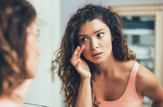 Jeune fille qui se regarde l'oeil dans le miroir