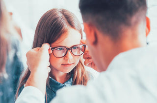 Une jeune fille essaie ses nouvelles lunettes avec son opticien.