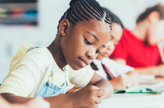 Jeune fille noire qui fait ses devoirs en classe