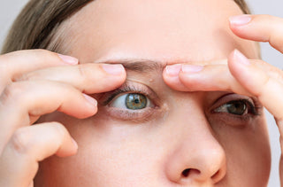 Une femme examine les grains de milium qu'elle a sur la paupière 