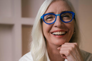 Une femme souriante avec des lunettes bleu électrique