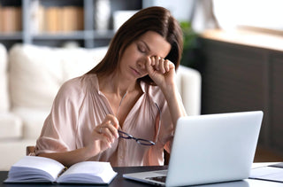 Une femme devant son ordinateur portable, se frotte les yeux