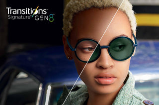 Une femme noire porte des lunettes noires et rondes avec lentilles Transitions. 