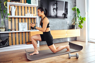 Une femme sur un tapis de yoga dans son salon fait une séance d'entraînement.