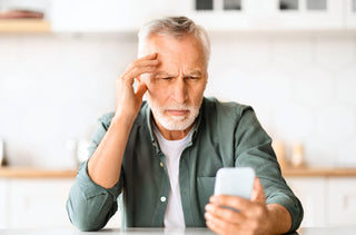 Un homme avec de la presbytie a de la diffulté à lire son téléphone cellulaire 