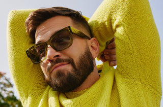 Un homme portant un chandail long jaune et des lunettes de soleil.