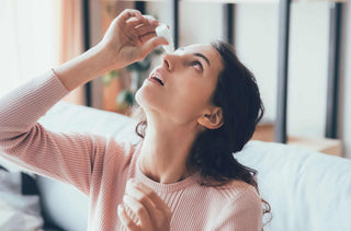 Une femme se met des gouttes dans les yeux