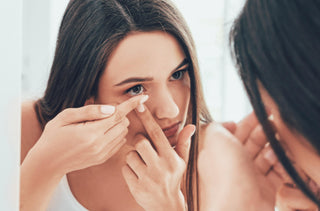 Jeune femme qui mets un verre de contact face au miroir