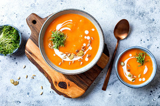 Soupe de citrouille et de carottes agrémentée de crème, de graines et de micropousses