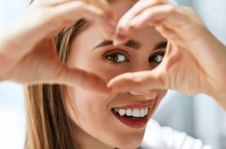 Femme regardant à travers ses mains qu'elle tient en forme de coeur