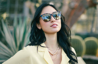 Une femme qui porte des lunettes de soleil et une robe jaune