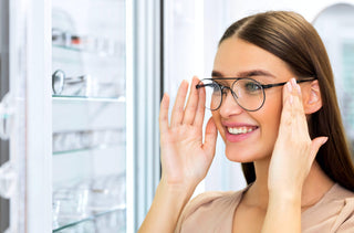 Une jeune femme essaie ses nouvelles lunettes aviateur chez l'optométriste.