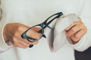 Personne qui nettoie ses lunettes de vue.