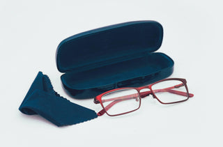 Une lunette rouge avec un étui et un linge à lunettes bleu