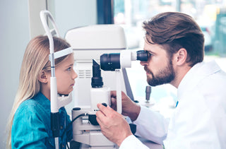 Un optomériste examine les yeux d'une jeune fille.