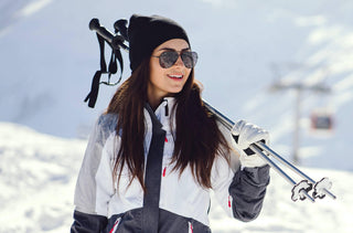 Une jeune femme avec des lunettes de soleil aviateur skiant dans les montagnes