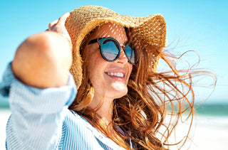 Une femme portant des lunettes de soleil et un chapeau à la plage