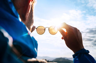 Un homme qui tient des lunettes de soleil vers le ciel