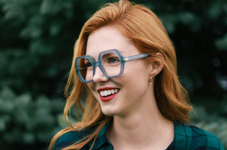 Une femme rousse porte des grandes lunettes bleues