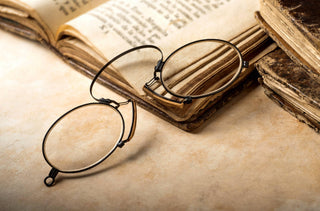 Ancien modèle de lunettes sans branches posé sur un livre ouvert