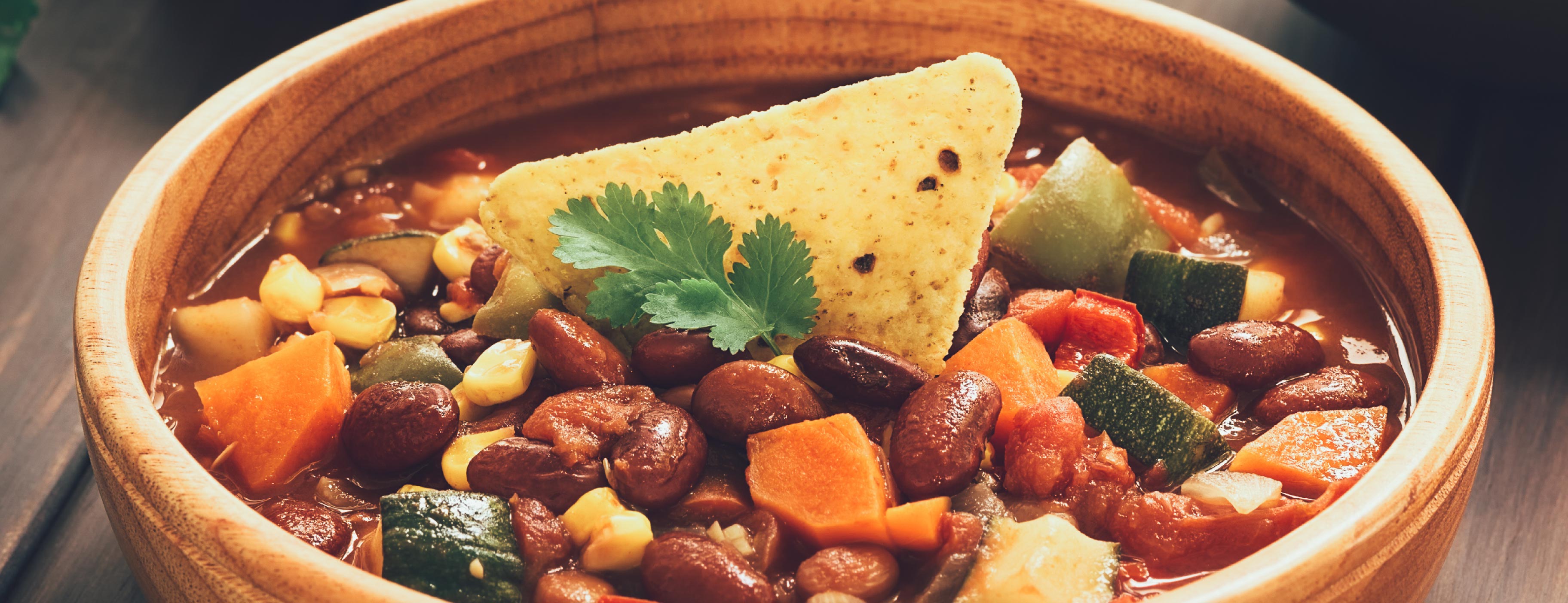 A bol of vegetarian chili with a tortilla chip is laid on a table