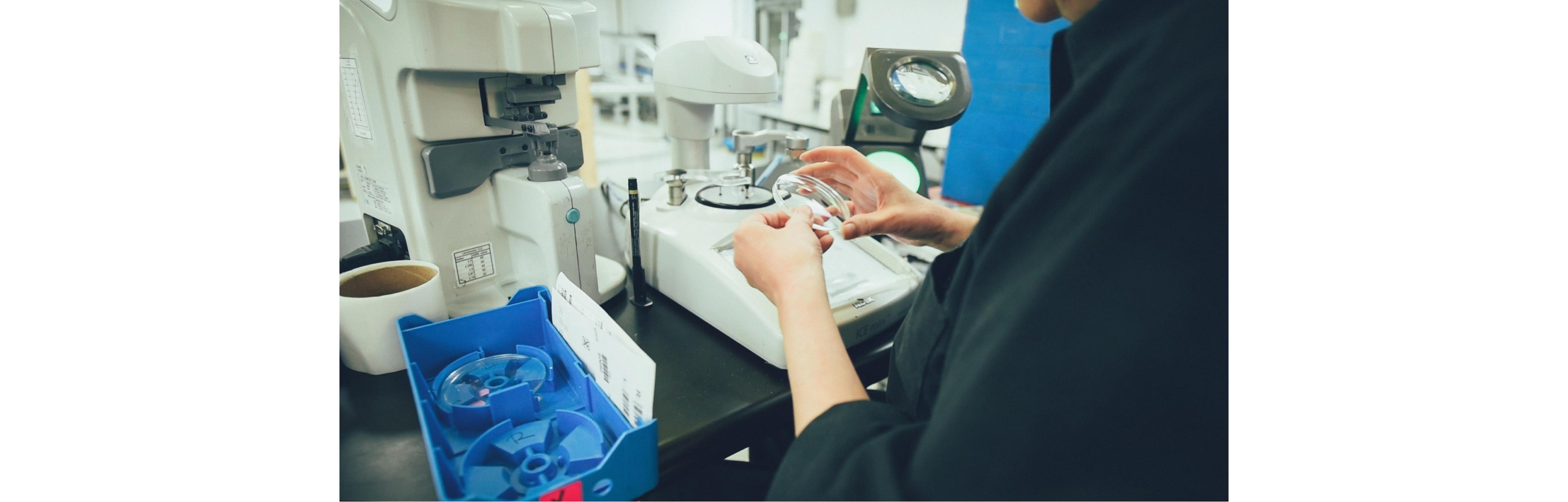 A Nikon employee is edging round nikon lenses using a machine
