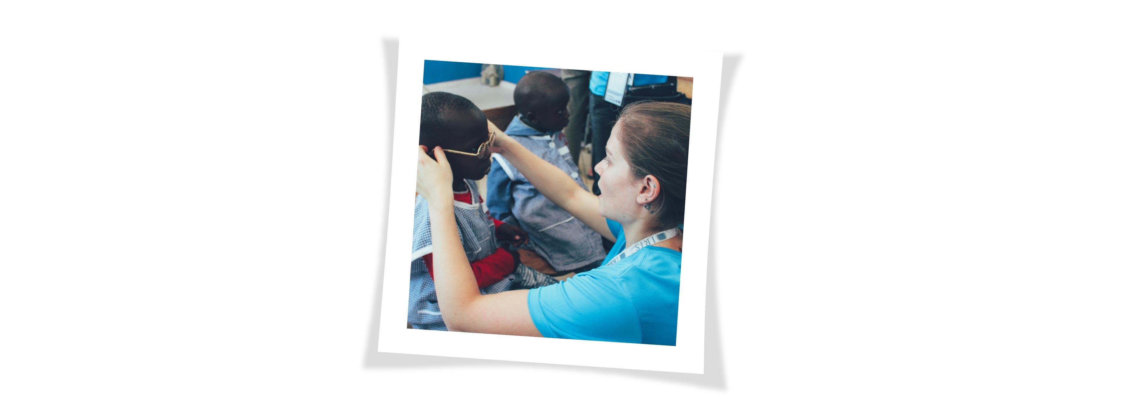 A volunteer is adjusting a young patient_s glasses 