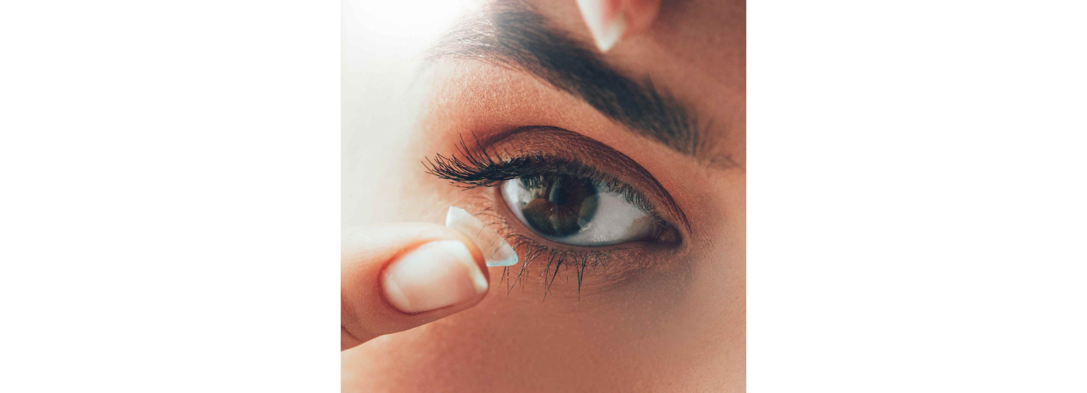 A woman is putting a contact lens in her eye