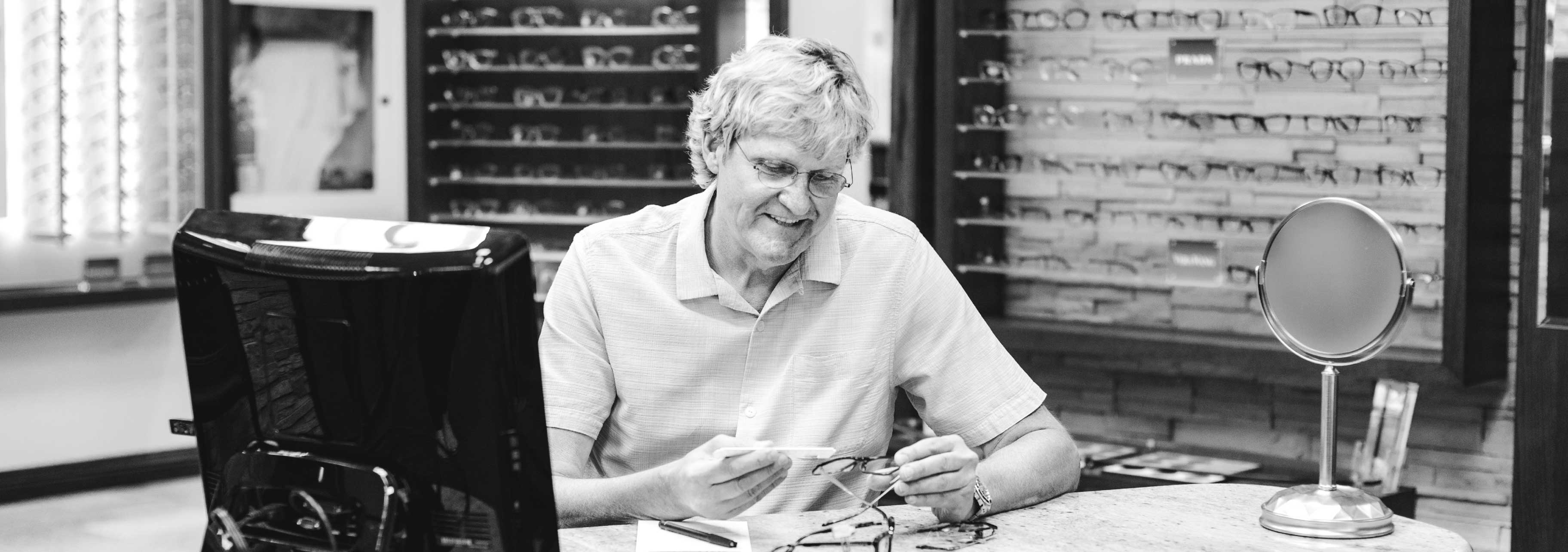 Perry Steigner est assis à son bureau d'opticien, il a des lunettes dans les mains