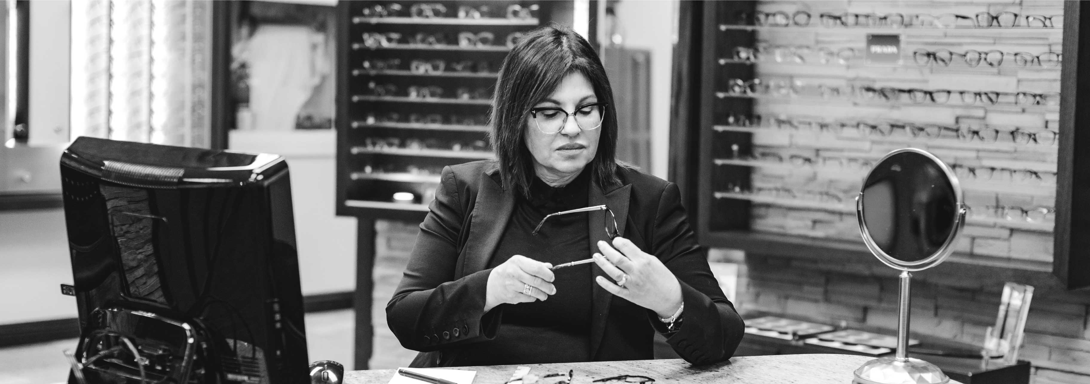 Rose Chiarot assise à son bureau d'opticienne, elle a des lunettes dans les mains